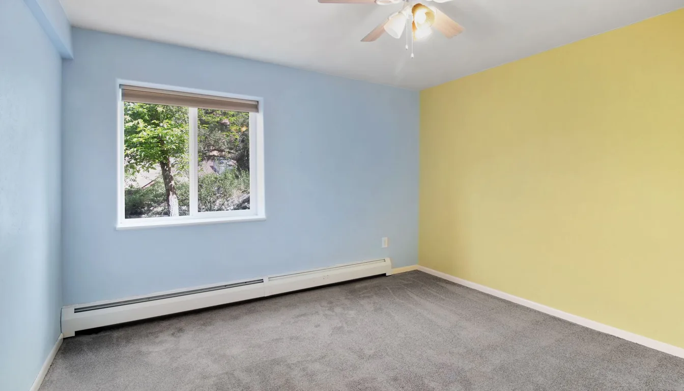 An electric baseboard heater along a bright room wall